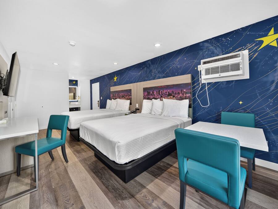 Habitación de hotel con cama, dos sillas, un escritorio y una pared con diseño de noche estrellada.