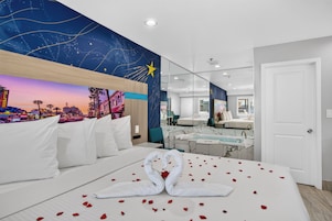 Habitación de hotel con cama, un espejo grande, un mural del cielo nocturno y vistas de la ciudad.