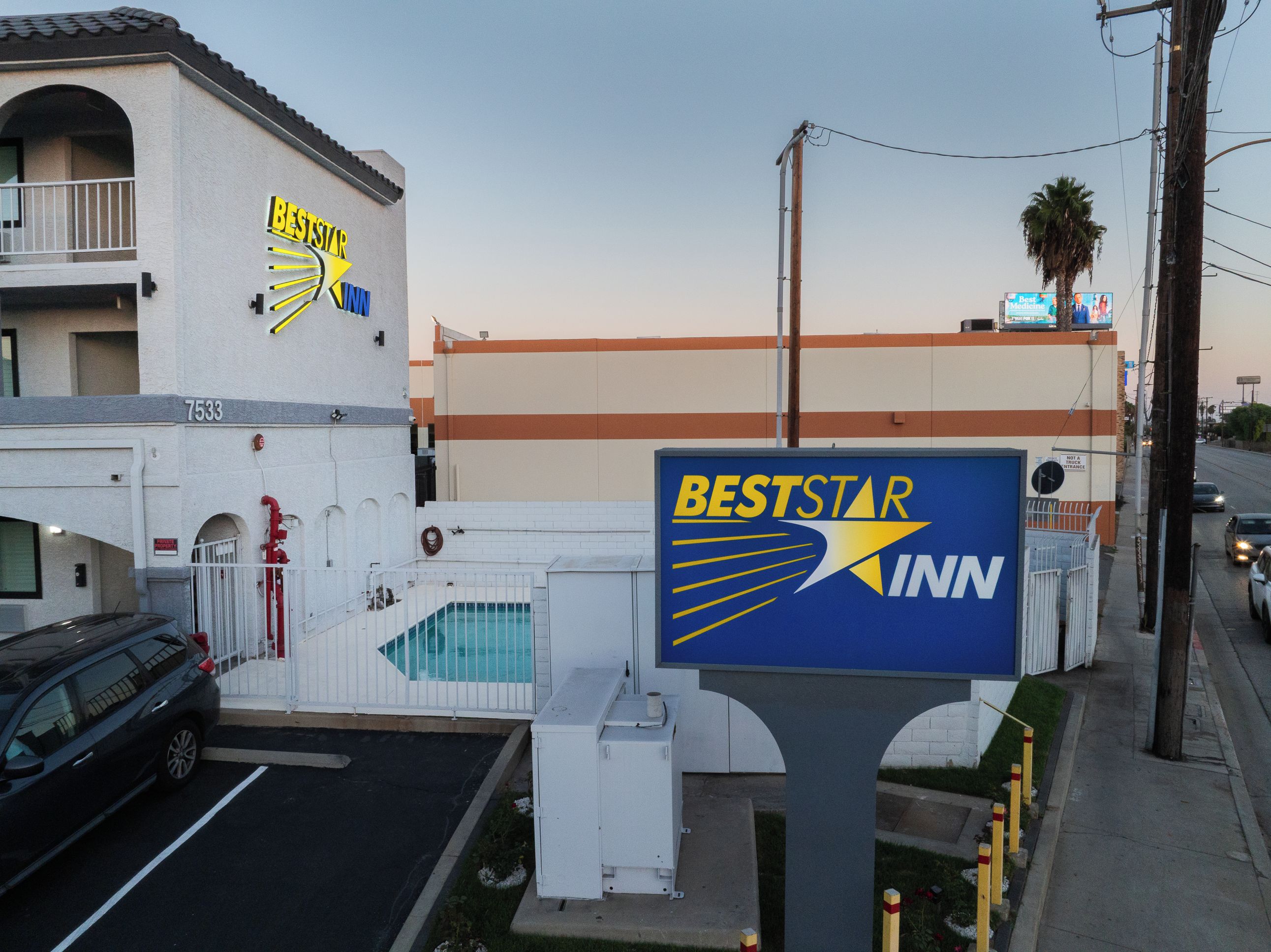 Señal de BestStar Inn con zona de piscina y un edificio con balcón.