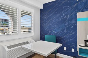 A room with a window, a table, a chair, and a wall with a starry design.