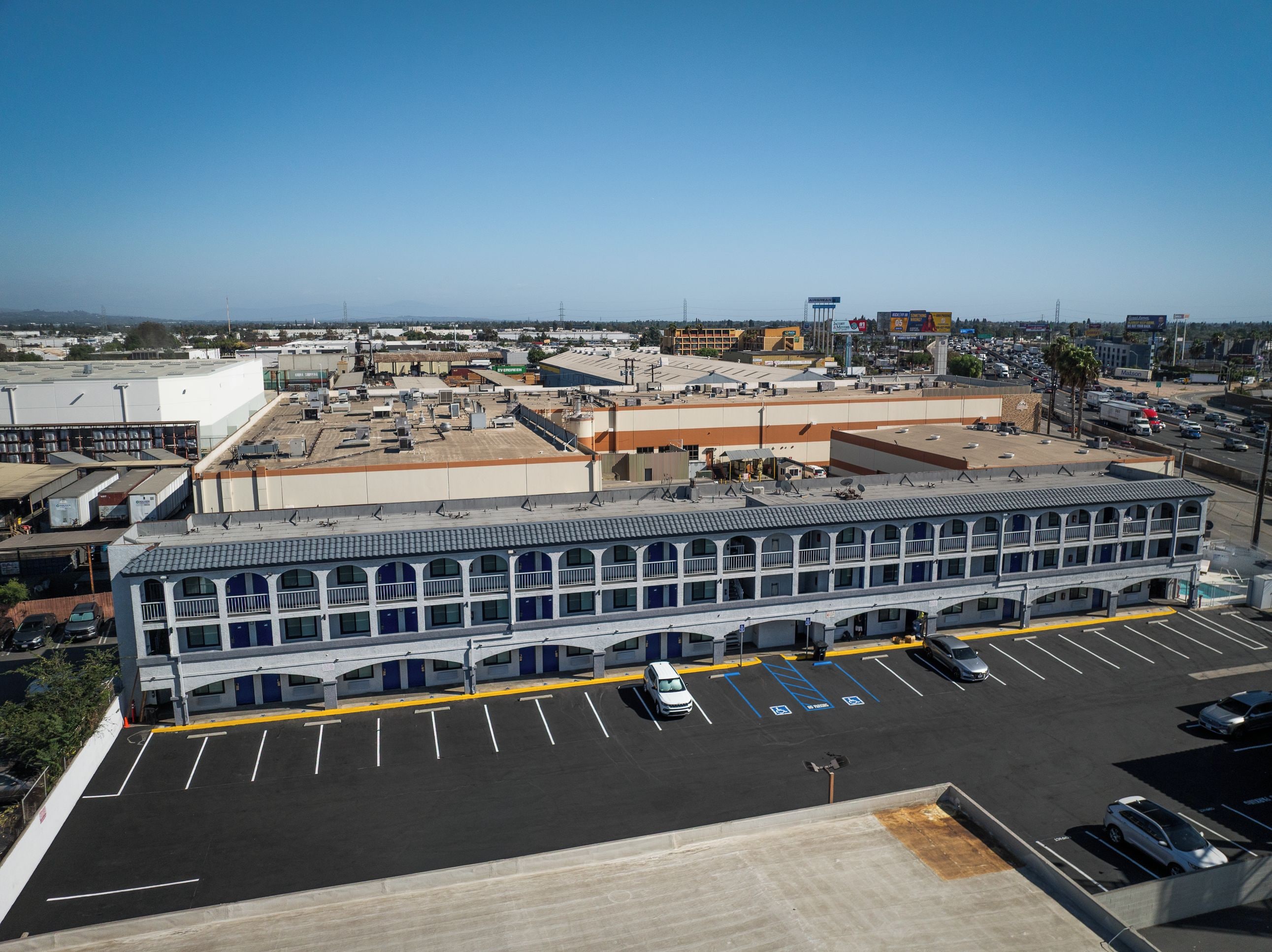 A multi-story hotel with a parking lot and a view of the surrounding cityscape.