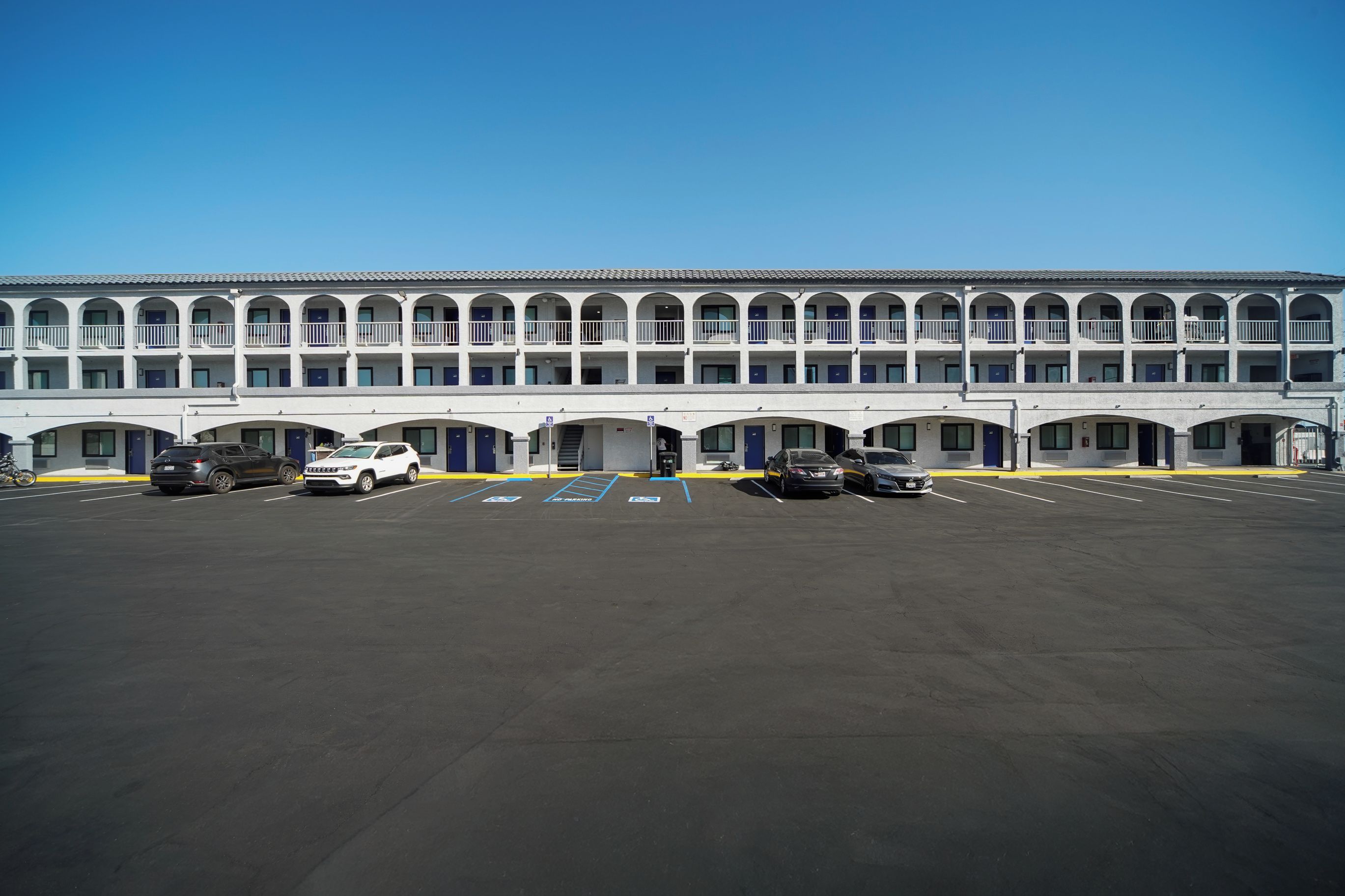 Un immeuble à plusieurs étages, avec une rangée de pièces, un parking et un ciel dégagé.