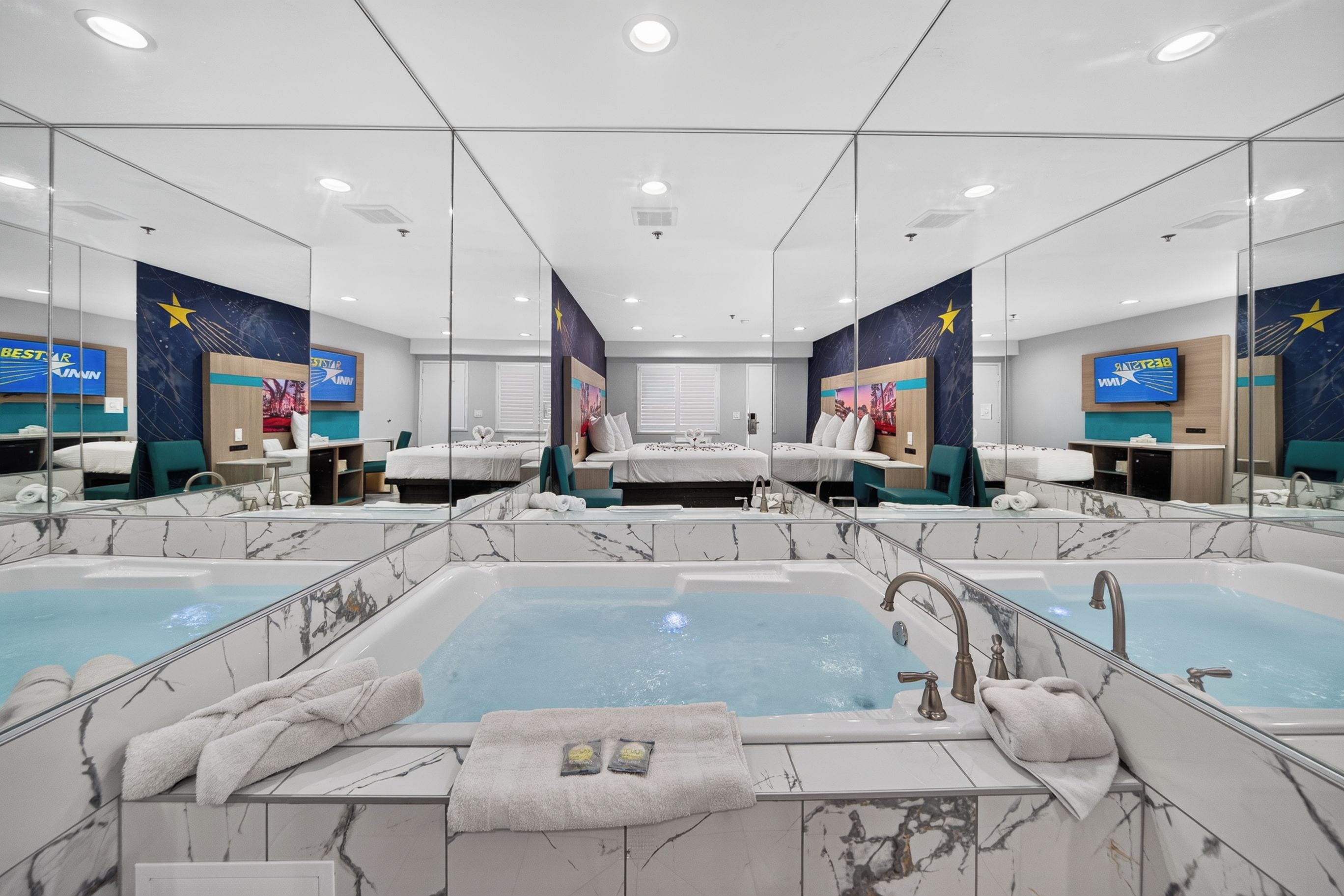 A hotel bathroom with two large tubs, mirrors, and a star-themed wall mural.