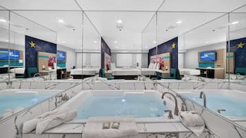 A hotel bathroom with two large tubs, mirrors, and a star-themed wall mural.
