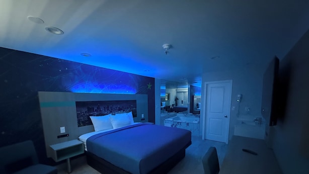 Une chambre à coucher moderne avec un lit, des tables de chevet, un bureau et une chaise.
