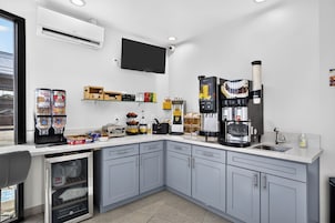 Una cocina moderna con armarios grises, horno integrado, cafetera y diversos alimentos sobre la encimera.