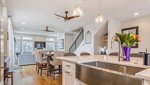 Una cocina moderna con una isla grande, electrodomésticos de acero inoxidable e iluminación colgante.