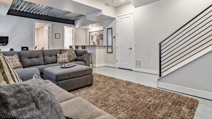 Una sala moderna con un sofá modular, un pequeño reposapiés y una alfombra estampada.