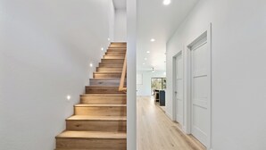 Una escalera de madera que conduce a una habitación, donde se ve un área de cocina al fondo.