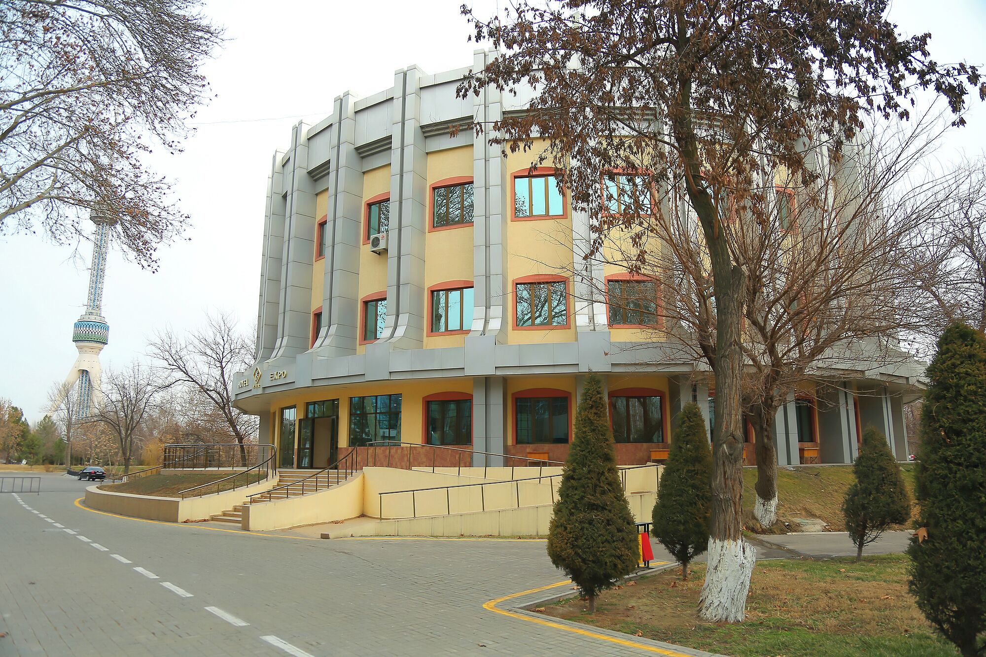 A multi-story building with a yellow facade, large windows, and a staircase leading to the entrance.
