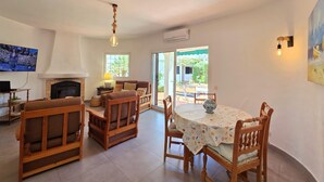A cozy living room with a fireplace, a television, and a dining area with a table and chairs.
