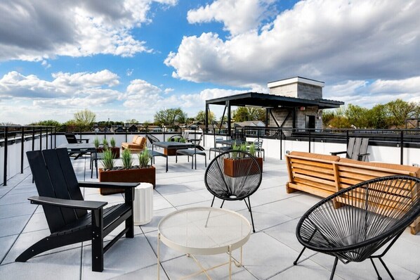 A rooftop terrace with outdoor seating, including chairs and tables, and a view of the surrounding area. - East Nash Top-Floor 1BR | Rooftop Deck | Sleeps 6 (Nashville)