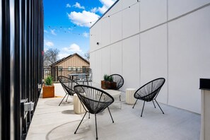 Une terrasse extérieure avec des chaises à armature métallique noire, une petite table et des plantes en pot.