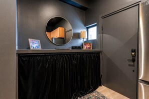 Una habitación con cortina de terciopelo negro, un espejo redondo y una puerta con cerradura de llave.