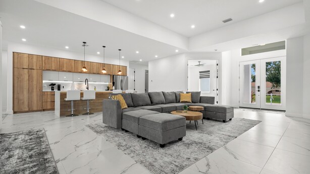 A modern kitchen with wooden cabinets, a grey sectional sofa, and a round coffee table. - Luxury 3-bedroom Villa with Heated pool and spa (Rotonda West)