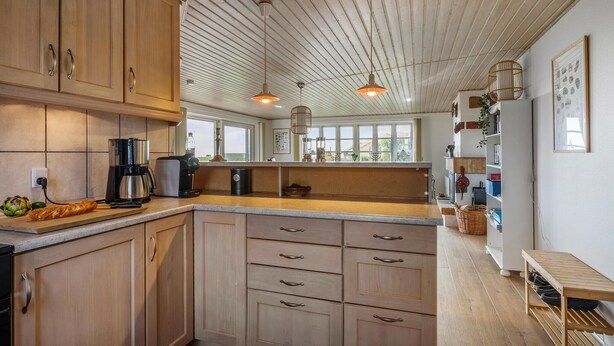 A modern kitchen with wooden cabinets, a central island, and pendant lighting. - Pet friendly home in Slagelse with WiFi (Slagelse)