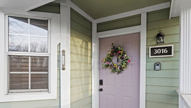 A house with a purple door, a welcome mat, and a number sign '3016' on the wall. - Sunset Cottage (Fairfield Bay)