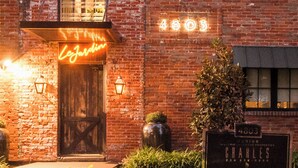 Ein Backsteinhaus mit einem Neonlichtschild, auf dem "Le Jardin" steht, und einer Plakette mit der Aufschrift "4803".