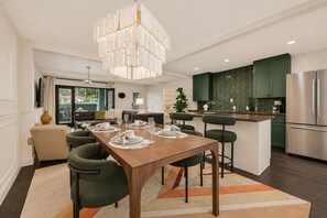 A modern kitchen with green cabinets, a stainless steel refrigerator, and a dining area with a wooden table set for four. - An inviting two-bedroom condo with a bright open layout, tranquil garden views, and a private patio overlooking a beautifully landscaped courtyard and pool.🎡 STAY MINUTES FROM THE STATE FAIR OF TEXAS! 🎡 (Dallas)