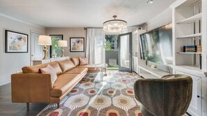 Un salon moderne avec un canapé en cuir, une table basse en verre et un tapis à motifs.