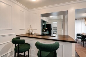 A kitchen with a central island, two bar stools, and a large mirror above the island.