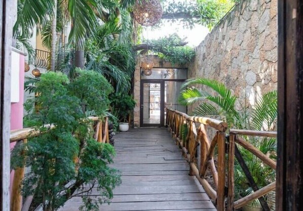 Stroll through lush gardens to the entrance, flanked by a stone wall and a wooden railing.