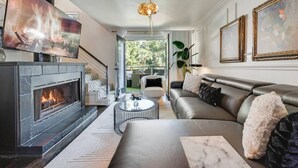 A modern living room with a fireplace, a leather sofa, a coffee table, and a television.