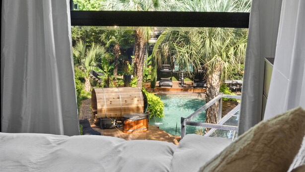 A bedroom with a view of a pool and outdoor seating area.