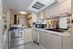 A modern kitchen with stainless steel appliances, a built-in microwave, and a sink.