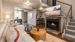 Una sala de estar moderna con chimenea, televisor y escalera.