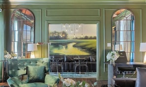A lobby with a large painting of a landscape, a green armchair, a sofa, and a dining area with a table and chairs. - Zen Loft with dual king beds, resort-style pool, and luxury amenities. (Dallas)