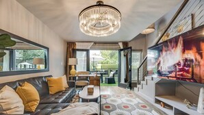 A modern living room with a leather sofa, a chandelier, and a fireplace. - 2-level Spacious loft   with pool, private patio, and historic charm. (Dallas)