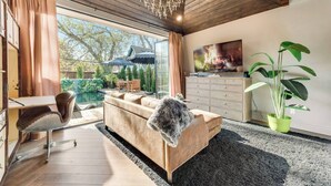 Ein modernes Wohnzimmer mit einer Couch, einem Couchtisch, einem Fernseher und einer großen Pflanze.