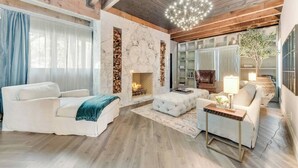 Ein modernes Wohnzimmer mit Kamin, Holzbalken und einer Kristallleuchter.