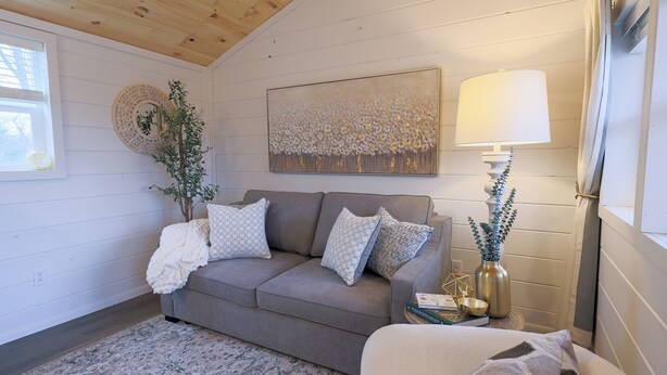 A cozy living room with a grey sofa, patterned cushions, a decorative mirror, a painting, and a lamp. - Private Cabin - Hiking. Getaway. Near the ARK. No Cleaning Fees (Corinth)