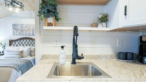 Een keuken met een roestvrijstalen spoelbak, een zwarte kraan en een marmeren aanrecht.