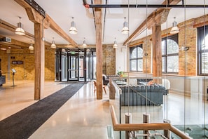 A modern lobby with exposed brick walls, a glass railing, and a central seating area.