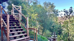 A wooden staircase leading to a garden area with a fountain and lush greenery. - Peaceful LA Retreat w/ King Bed, Hot Tub and Mountain Views! Enjoy the Outdoors (Topanga)