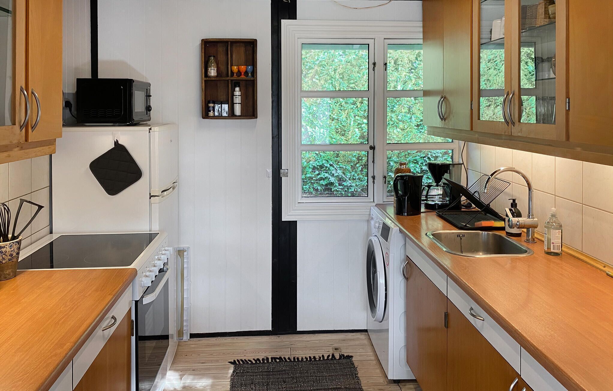 A compact kitchen with a washing machine, a microwave, and a coffee maker.