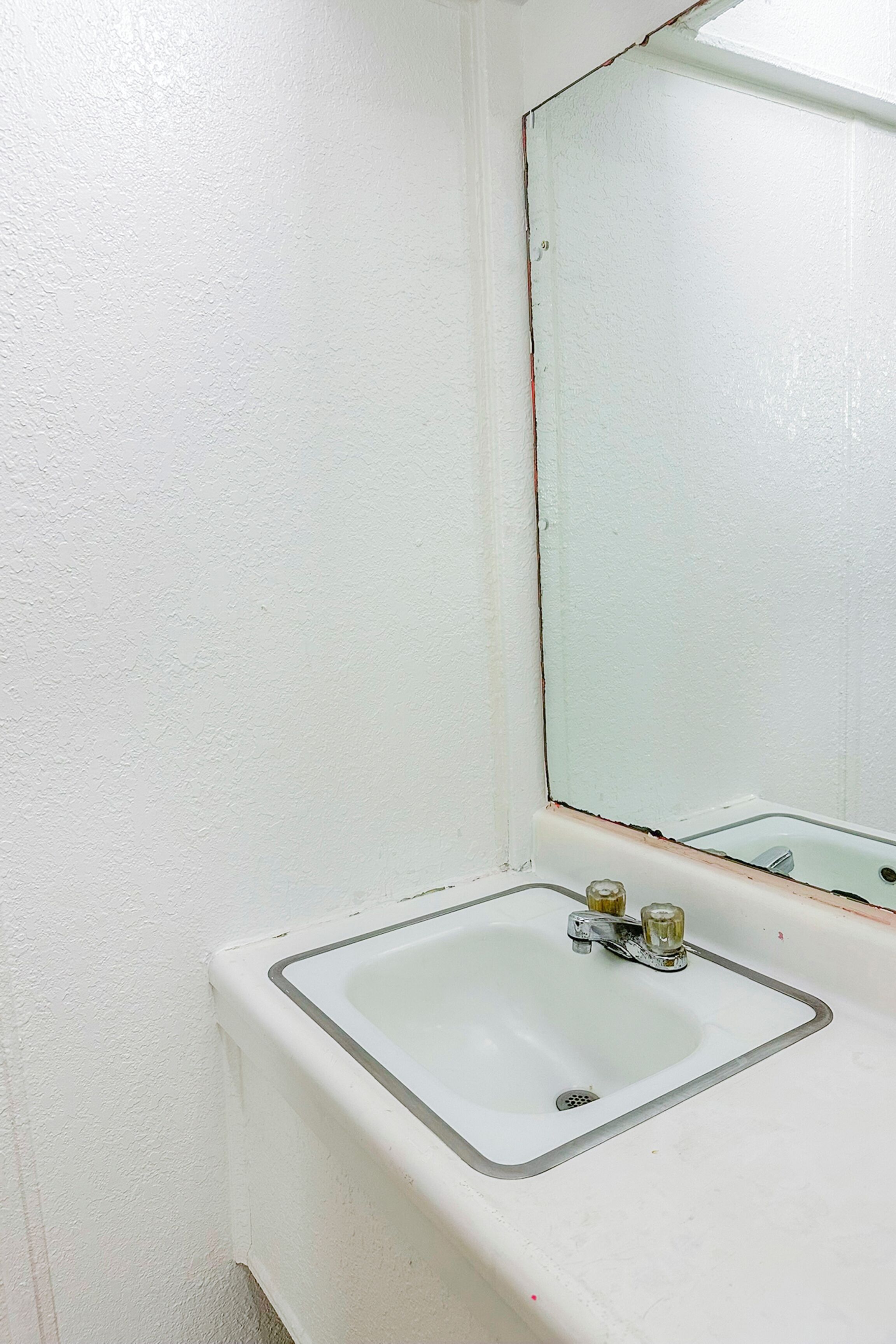 Un bany blanc amb un lavabo rectangular i un mirall a la part superior.