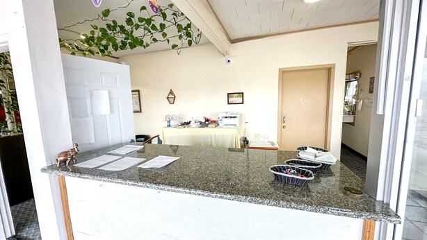 A reception area with a counter, a table with chairs, and a door in the background.
