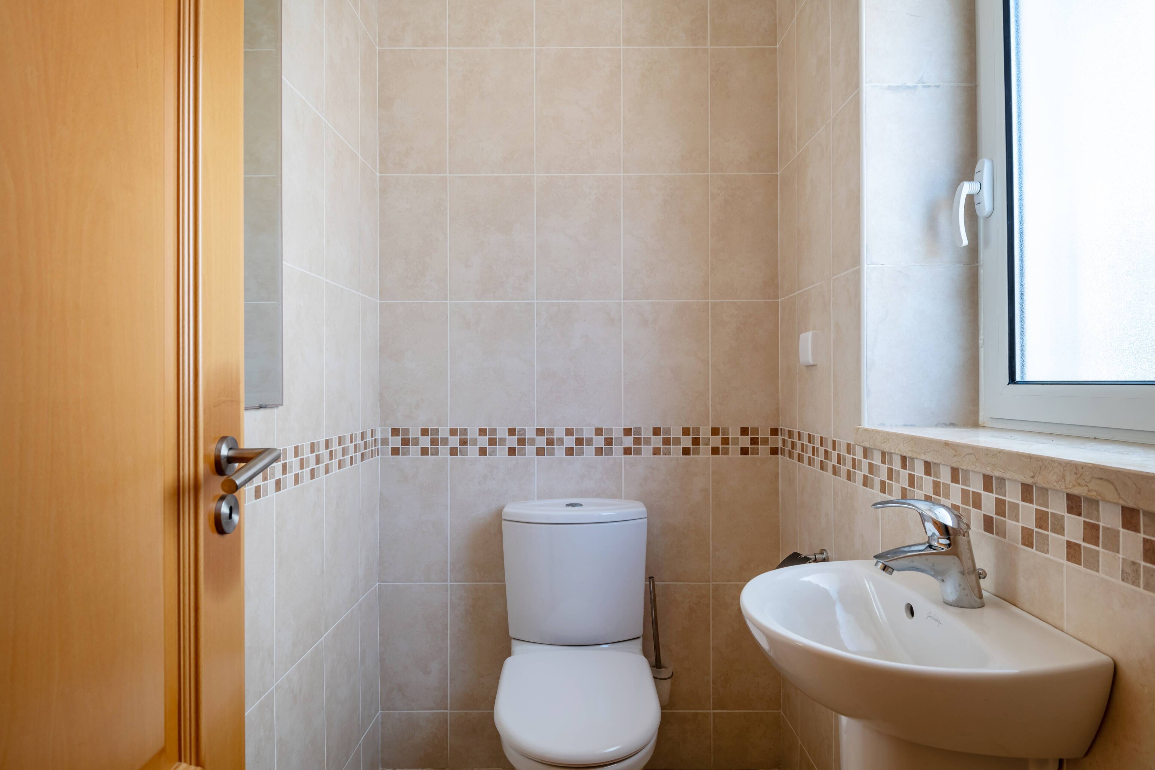 A bathroom with a toilet, sink, and a window.