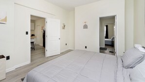 A spacious bedroom with a large bed, a walk-in closet, and a bathroom visible through an open door.