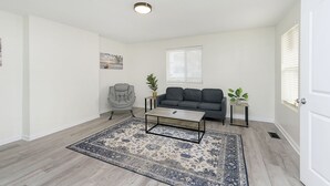 A living room with a gray sofa, a gray armchair, a coffee table, and a patterned rug.