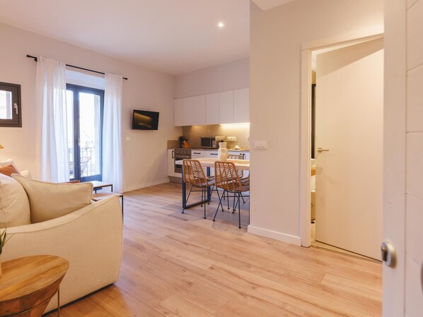 A modern apartment with a living room, dining area, and kitchen.