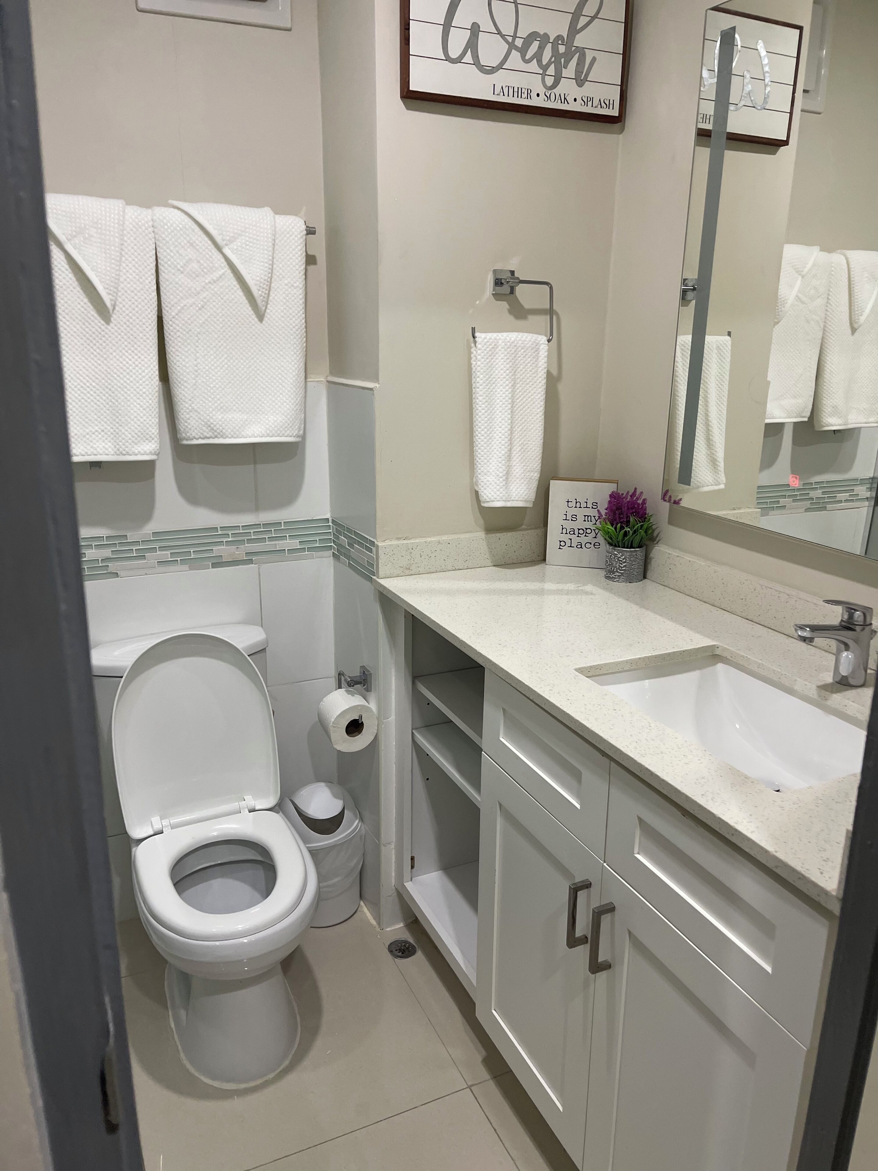 Een badkamer met toilet, wastafel, spiegel en handdoeken.