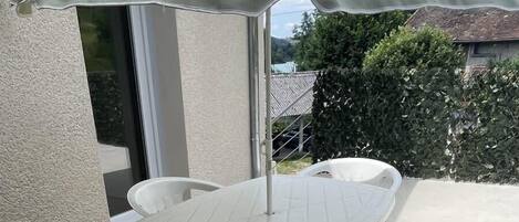 A patio table with a white umbrella, surrounded by white plastic chairs.