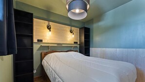 A bedroom with a wooden headboard, a bed with white bedding, and a ceiling light fixture.