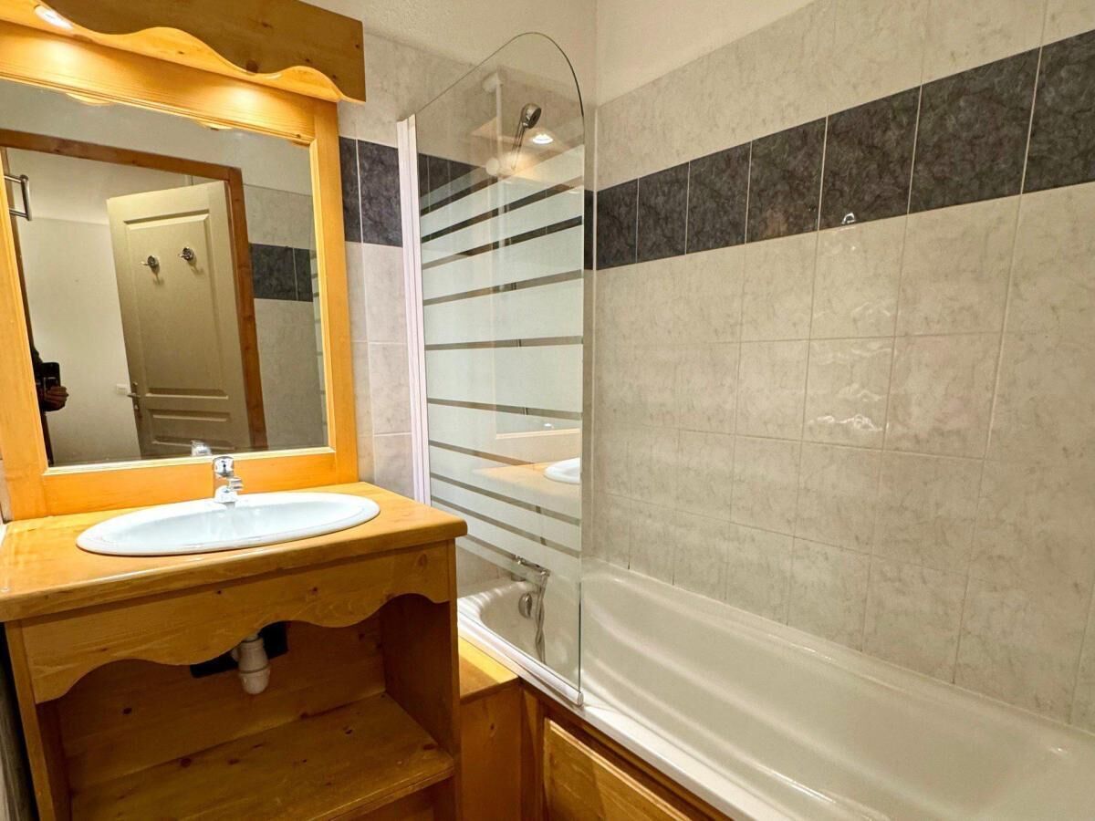 Un bagno con un mobile vanitario in legno, un lavandino bianco, uno spazio doccia in vetro e una vasca da bagno.