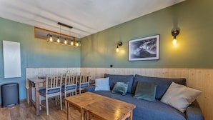 Una sala de estar acogedora con una mesa de comedor de madera, sofá azul y un cuadro en la pared.